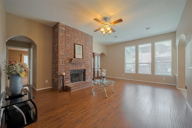 21619 Oakcreek Ct, Katy, TX 77450 - living room featuring a ceiling fan, a brick fireplace, wood finished floors, and arched walkways