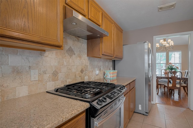 21619 Oakcreek Ct, Katy, TX 77450 - kitchen featuring appliances with stainless steel finishes, extractor fan, a chandelier, light tile patterned flooring, and light countertops