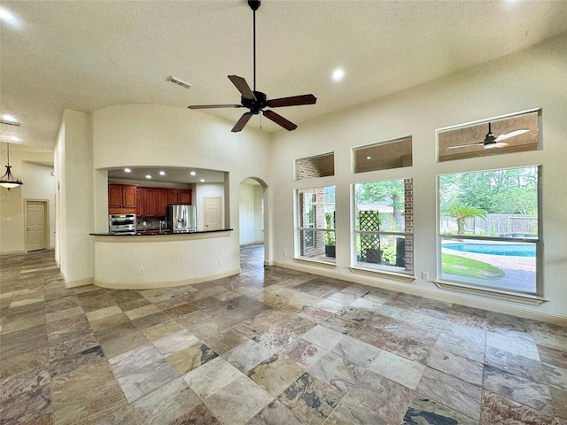 8110 Hideaway Run Way, Spring, TX 77389 - unfurnished living room featuring a ceiling fan, arched walkways, recessed lighting, stone tile flooring, and a textured ceiling