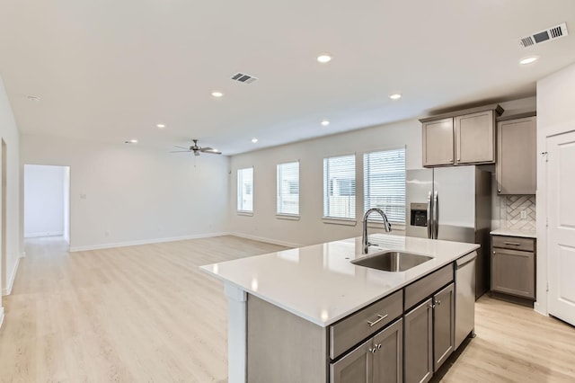 19367 Poppy Village Cir, Magnolia, TX 77355 - kitchen featuring stainless steel appliances, light wood finished floors, a ceiling fan, tasteful backsplash, and light countertops
