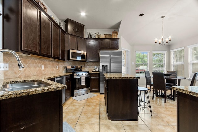423 Carson Ridge Dr, Spring, TX 77386 - kitchen featuring appliances with stainless steel finishes, dark stone counters, dark brown cabinetry, decorative backsplash, and a kitchen island