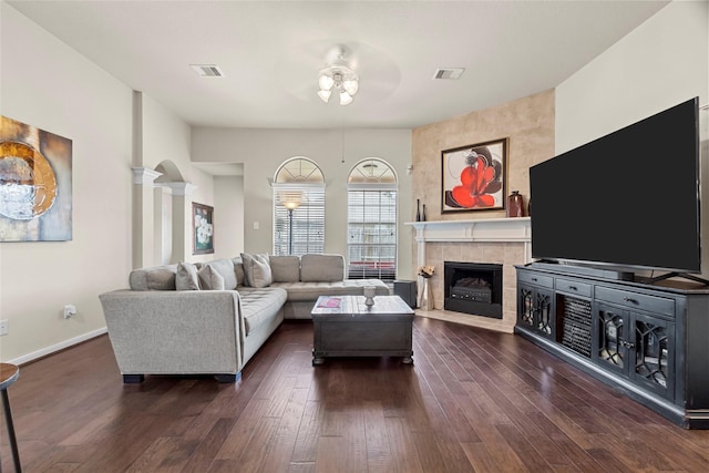 423 Carson Ridge Dr, Spring, TX 77386 - living room featuring ceiling fan, a tiled fireplace, dark wood-style flooring, and decorative columns