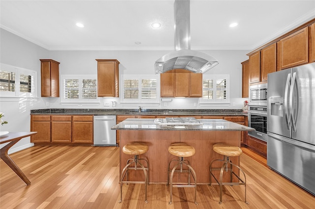 2043 W 14th 1/2 St, Houston, TX 77008 - kitchen featuring appliances with stainless steel finishes, island exhaust hood, a breakfast bar, brown cabinetry, and ornamental molding