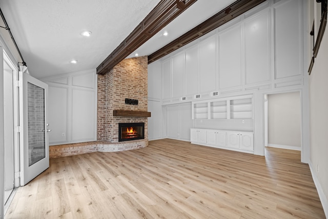3503 Arbor Terrace Ct, Spring, TX 77388 - unfurnished living room featuring a decorative wall, light wood finished floors, a fireplace, high vaulted ceiling, and beam ceiling