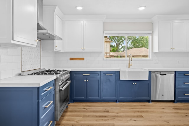 3503 Arbor Terrace Ct, Spring, TX 77388 - kitchen with stainless steel appliances, blue cabinets, wall chimney range hood, light countertops, and crown molding