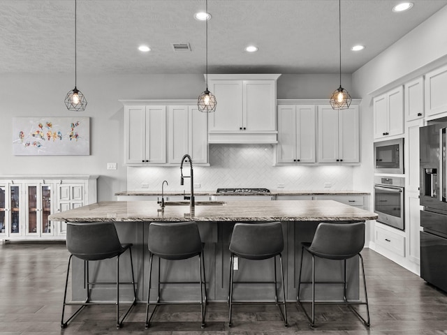 3723 Kerr Commons Ln, Houston, TX 77059 - kitchen with appliances with stainless steel finishes, tasteful backsplash, white cabinetry, an island with sink, and recessed lighting