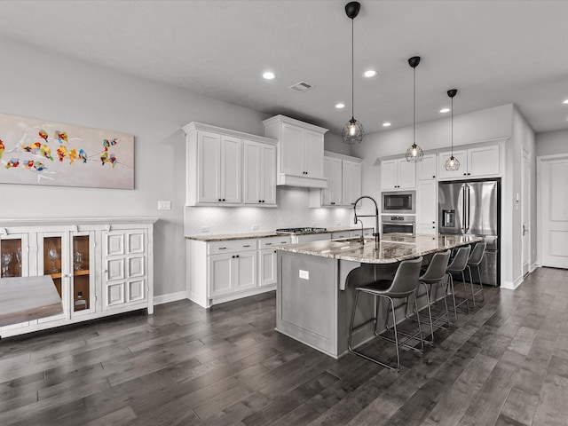 3723 Kerr Commons Ln, Houston, TX 77059 - kitchen featuring appliances with stainless steel finishes, white cabinetry, recessed lighting, light stone counters, and a kitchen island with sink