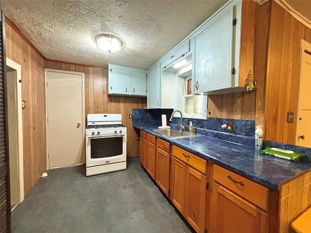 1410 W Pavillion St, Woodville, TX 75979 - kitchen featuring white gas range oven, wood walls, dark countertops, brown cabinetry, and a textured ceiling
