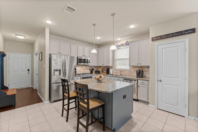 23707 Pennington Hills Dr, Spring, TX 77389 - kitchen featuring appliances with stainless steel finishes, tasteful backsplash, a breakfast bar, a kitchen island, and white cabinets