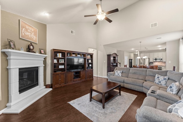 23707 Pennington Hills Dr, Spring, TX 77389 - living room featuring dark wood-type flooring, a ceiling fan, a glass covered fireplace, and high vaulted ceiling