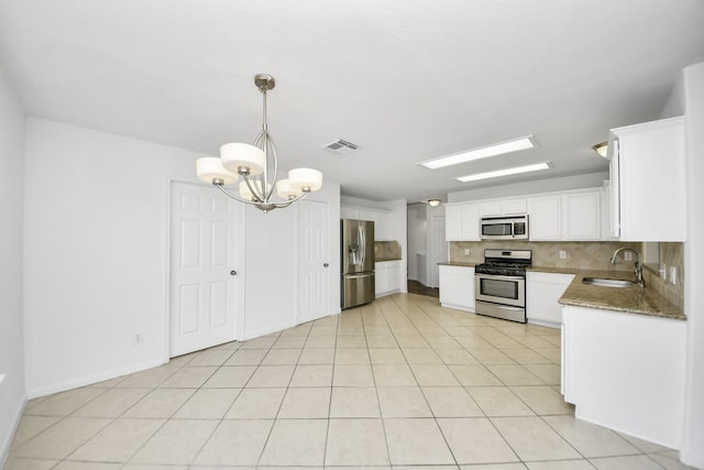 32310 Archer Park, Conroe, TX 77385 - kitchen featuring appliances with stainless steel finishes, a chandelier, backsplash, and white cabinetry