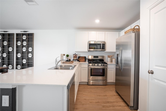10808 Red Orchid Dr, Houston, TX 77016 - kitchen with stainless steel appliances, a peninsula, light countertops, light wood finished floors, and white cabinets