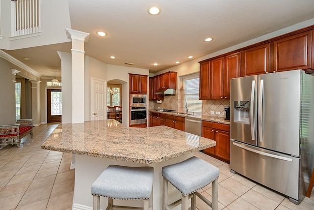 806 Spring Mist Ct, Sugar Land, TX 77479 - kitchen featuring stainless steel appliances, light tile patterned floors, decorative backsplash, light stone counters, and a kitchen bar