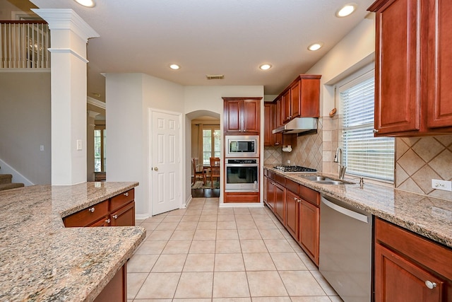 806 Spring Mist Ct, Sugar Land, TX 77479 - kitchen with stainless steel appliances, arched walkways, light stone counters, under cabinet range hood, and decorative backsplash