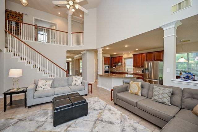 806 Spring Mist Ct, Sugar Land, TX 77479 - living room with ornate columns, light tile patterned floors, ceiling fan, stairs, and a high ceiling