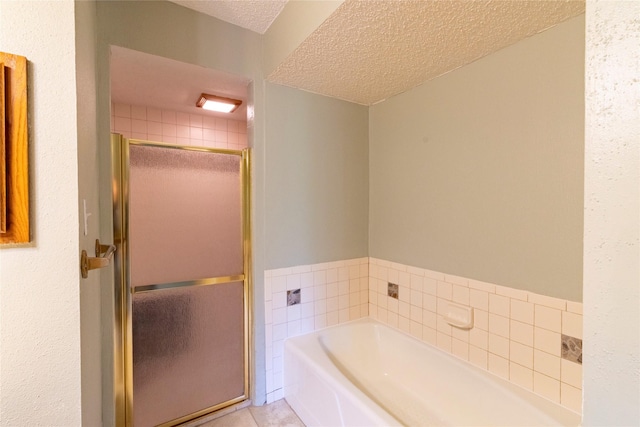 15823 Stagecoach Rd, Stagecoach, TX 77355 - full bath featuring a textured ceiling, a bath, a shower stall, and tile patterned floors