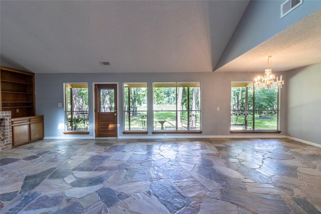 15823 Stagecoach Rd, Stagecoach, TX 77355 - unfurnished living room featuring vaulted ceiling, stone flooring, a chandelier, and built in shelves