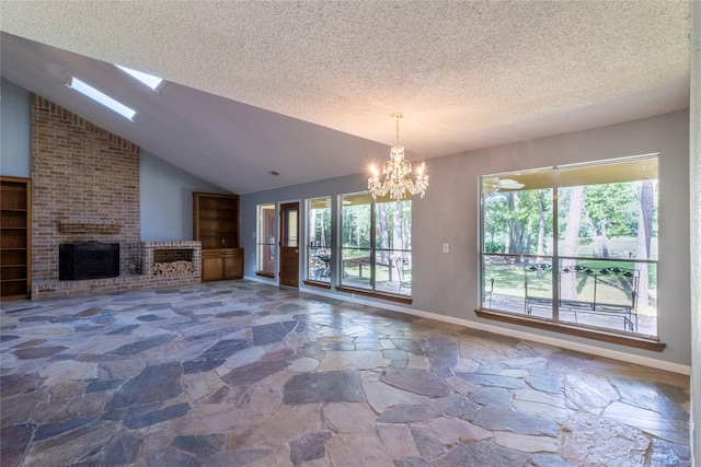 15823 Stagecoach Rd, Stagecoach, TX 77355 - unfurnished living room featuring stone flooring, a chandelier, plenty of natural light, a textured ceiling, and a brick fireplace