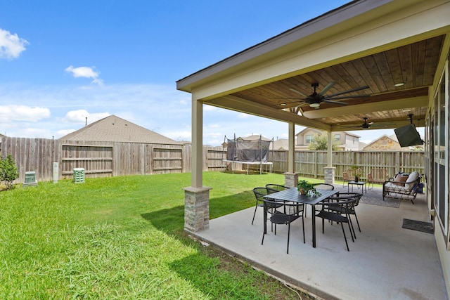 18402 Hilltop Climb Dr, Hockley, TX 77447 - fenced backyard with a trampoline, a ceiling fan, a patio area, and outdoor dining space