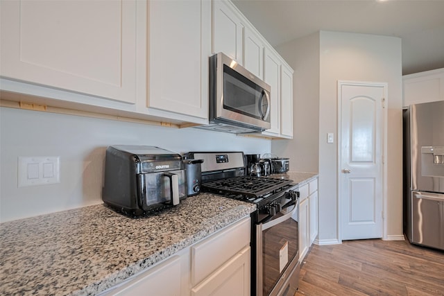 4315 Isoletta Ct, Katy, TX 77449 - kitchen featuring appliances with stainless steel finishes, light wood-type flooring, light stone countertops, and white cabinets