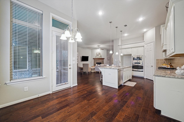 3030 Rabbit Brush Ln, Manvel, TX 77578 - kitchen with appliances with stainless steel finishes, open floor plan, dark wood-type flooring, white cabinets, and a fireplace