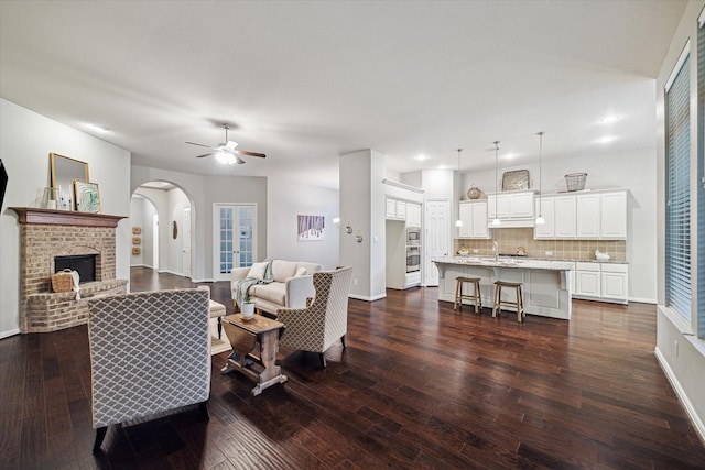3030 Rabbit Brush Ln, Manvel, TX 77578 - living room with dark wood-style floors, arched walkways, ceiling fan, a fireplace, and recessed lighting