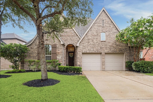 3030 Rabbit Brush Ln, Manvel, TX 77578 - tudor-style house with brick siding, a front yard, concrete driveway, and a garage