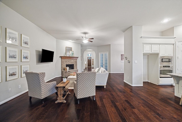 3030 Rabbit Brush Ln, Manvel, TX 77578 - living area with dark wood-style flooring, ceiling fan, a brick fireplace, and arched walkways