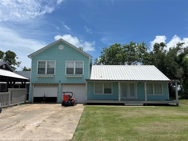 111 Duson Ave, Palacios, TX 77465 - view of front of house with concrete driveway, a front yard, an attached garage, and a metal roof
