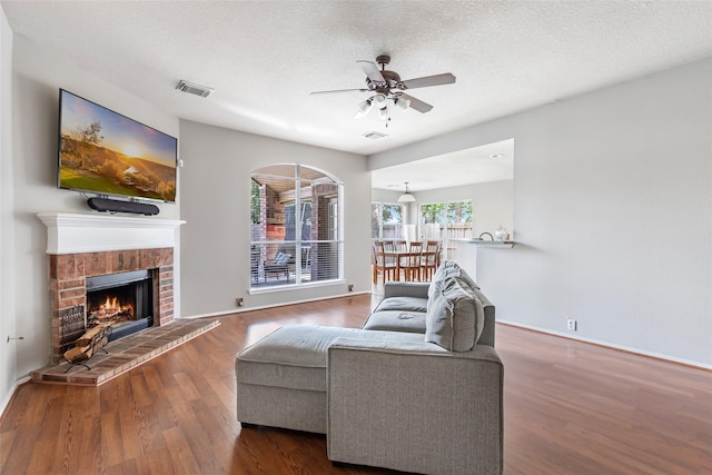 18618 Atascocita Forest Dr, Humble, TX 77346 - living room featuring wood finished floors, ceiling fan, a fireplace, and a textured ceiling