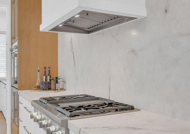 5602 Ella Lee Ln, Houston, TX 77056 - kitchen with ventilation hood, light countertops, stainless steel gas cooktop, and white cabinetry
