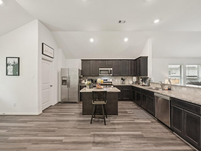 16129 Dockside St, Crosby, TX 77532 - kitchen with appliances with stainless steel finishes, lofted ceiling, a kitchen island, decorative backsplash, and light wood-type flooring