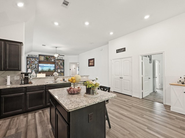 16129 Dockside St, Crosby, TX 77532 - kitchen featuring lofted ceiling, light wood-style flooring, a breakfast bar area, ceiling fan, and light stone countertops
