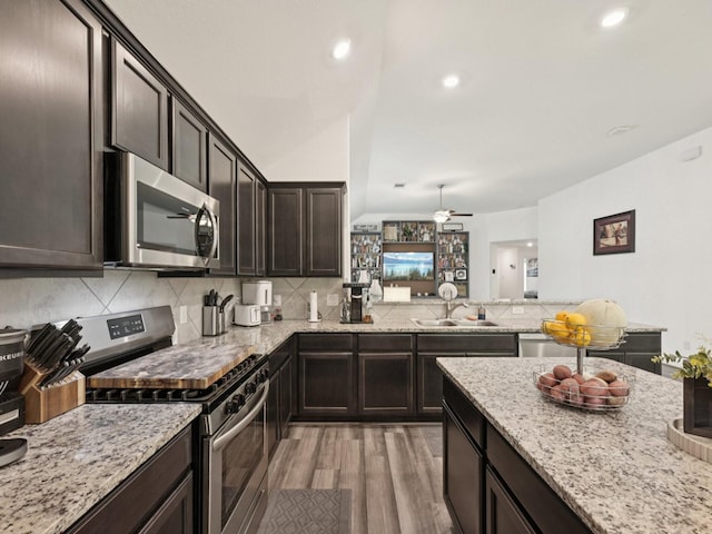 16129 Dockside St, Crosby, TX 77532 - kitchen featuring stainless steel appliances, light wood-style floors, decorative backsplash, dark brown cabinetry, and light stone counters