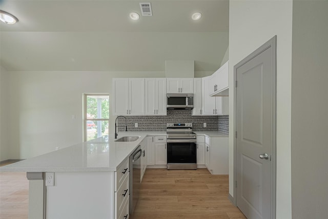 1909 Oregon St, Baytown, TX 77520 - kitchen featuring stainless steel appliances, a peninsula, decorative backsplash, light wood-type flooring, and light countertops