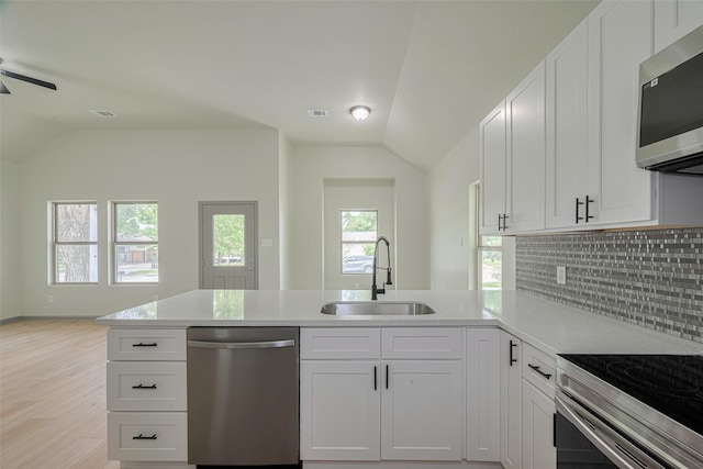 1909 Oregon St, Baytown, TX 77520 - kitchen with appliances with stainless steel finishes, vaulted ceiling, a peninsula, backsplash, and light wood-style floors