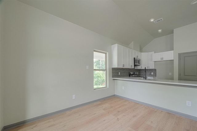 1909 Oregon St, Baytown, TX 77520 - kitchen featuring stainless steel appliances, lofted ceiling, light wood-type flooring, backsplash, and light countertops