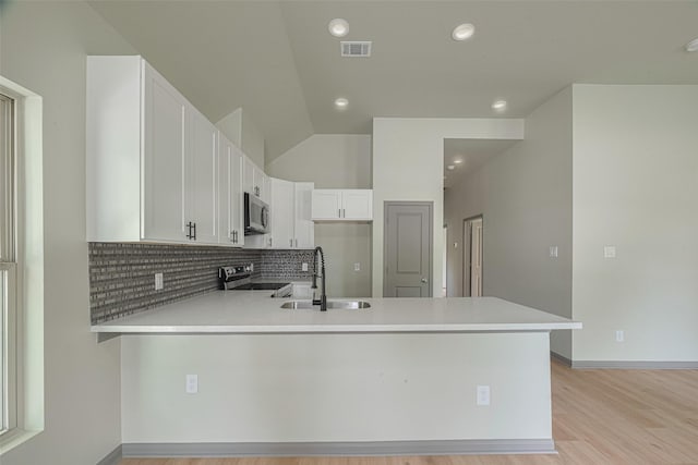 1909 Oregon St, Baytown, TX 77520 - kitchen with stainless steel appliances, a peninsula, decorative backsplash, light countertops, and white cabinetry