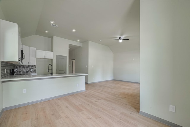 1909 Oregon St, Baytown, TX 77520 - kitchen with lofted ceiling, a ceiling fan, a peninsula, white cabinets, and tasteful backsplash
