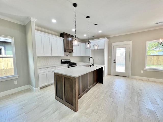 11841 12th St, Santa Fe, TX 77510 - kitchen featuring gas range oven, light countertops, backsplash, crown molding, and an island with sink
