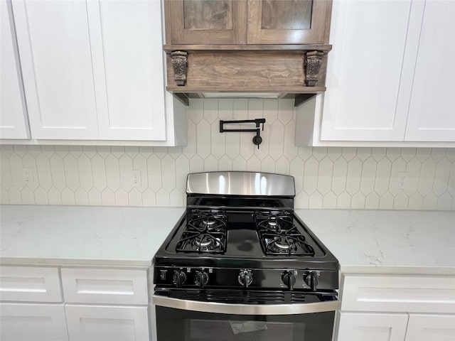 11841 12th St, Santa Fe, TX 77510 - kitchen featuring stainless steel gas range, white cabinetry, tasteful backsplash, custom exhaust hood, and light stone counters