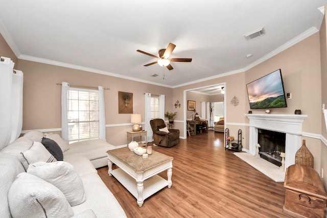 1503 Pine Ridge Ln, Pearland, TX 77581 - living room featuring ceiling fan, light wood-style floors, a fireplace with raised hearth, and ornamental molding