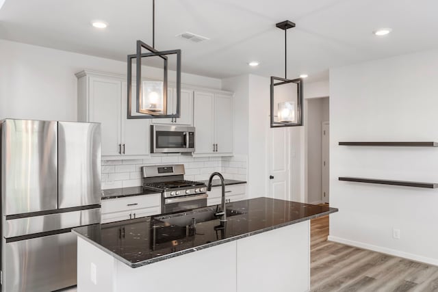 8722 Riverton Ridge Rd, Cypress, TX 77433 - kitchen with appliances with stainless steel finishes, light wood-style floors, tasteful backsplash, white cabinets, and dark stone countertops