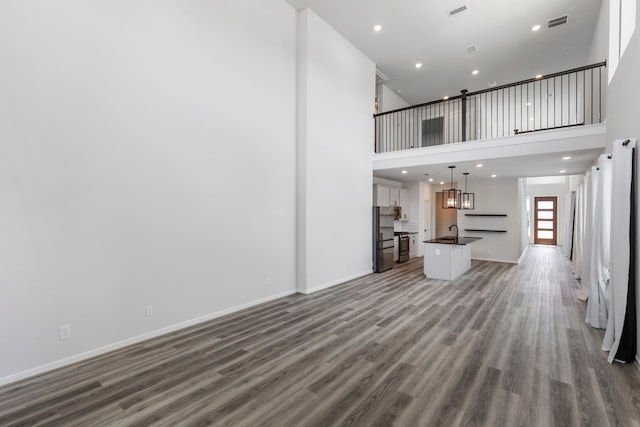 8722 Riverton Ridge Rd, Cypress, TX 77433 - unfurnished living room with wood finished floors, a high ceiling, and recessed lighting