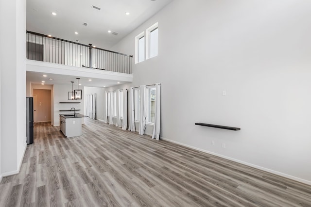 8722 Riverton Ridge Rd, Cypress, TX 77433 - unfurnished living room with light wood-type flooring, a high ceiling, and recessed lighting