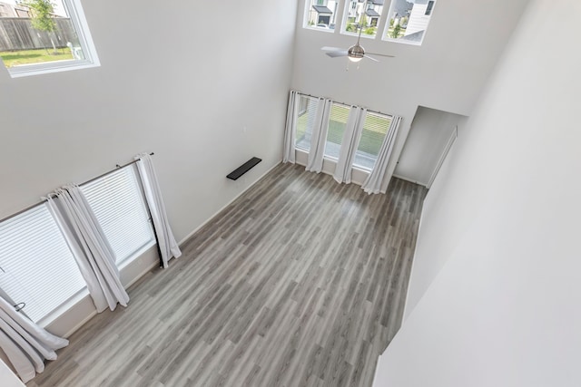 8722 Riverton Ridge Rd, Cypress, TX 77433 - unfurnished living room with a towering ceiling, healthy amount of natural light, a ceiling fan, and light wood-style floors