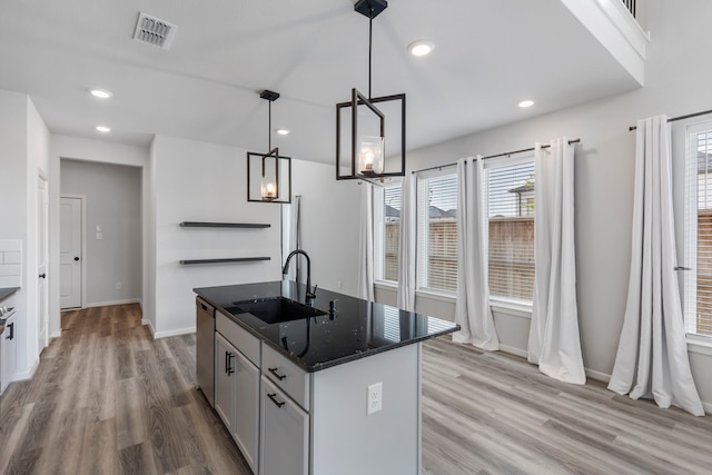 8722 Riverton Ridge Rd, Cypress, TX 77433 - kitchen with light wood-style floors, healthy amount of natural light, dark stone countertops, a kitchen island with sink, and recessed lighting
