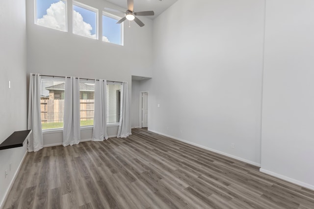 8722 Riverton Ridge Rd, Cypress, TX 77433 - unfurnished living room featuring ceiling fan, a high ceiling, and wood finished floors