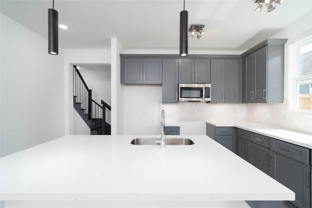 4417 Aledo St, Houston, TX 77051 - kitchen with stainless steel microwave, gray cabinetry, hanging light fixtures, and tasteful backsplash