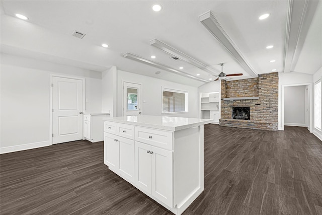 639 Ames St, Spring, TX 77373 - kitchen featuring dark wood-type flooring, a center island, ceiling fan, white cabinets, and a brick fireplace